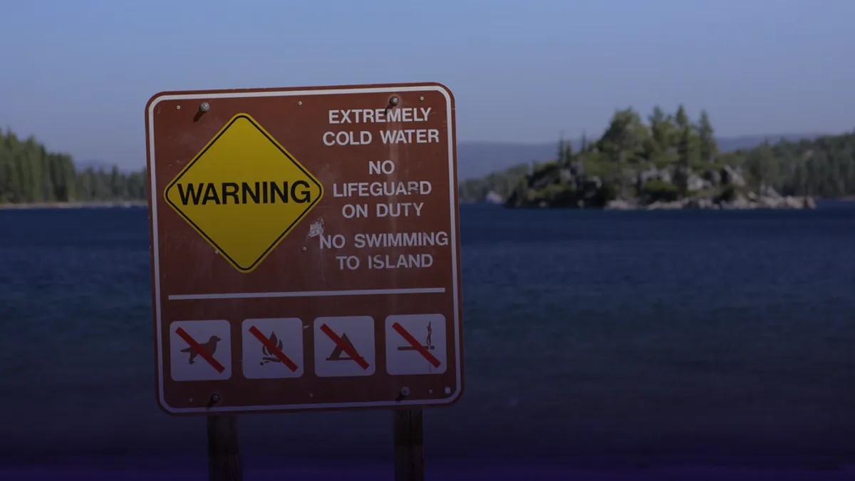 Warnschild vor gefährlichem Baden an einem Seeufer im Sommer